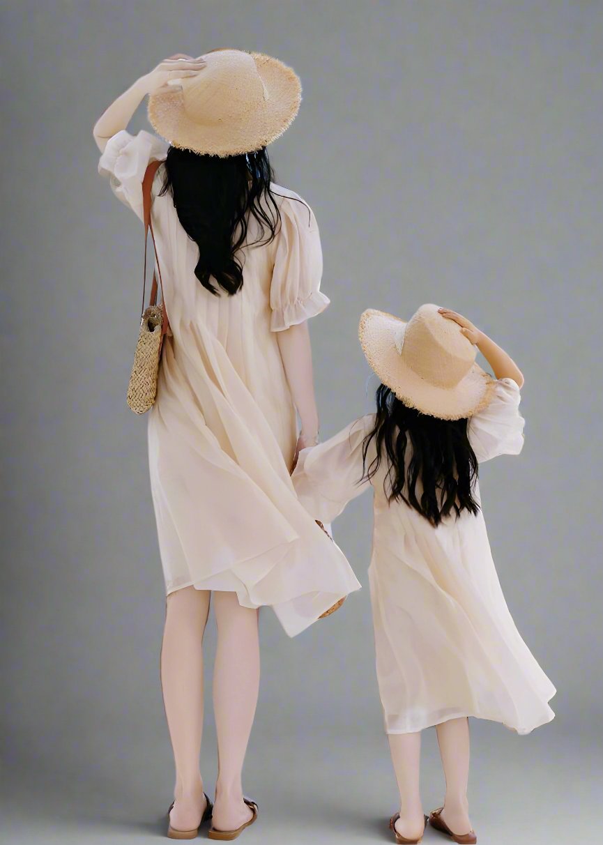 Family beach outing with mother and daughter in coordinating beige dresses