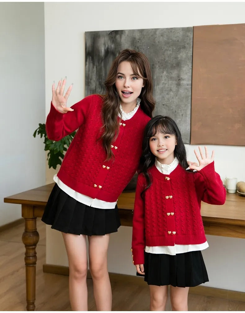 Mother and daughter waving in matching red cardigans with gold buttons and black skirts, showcasing stylish family outfits
