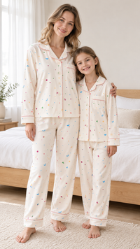 Mom and daughter in matching cream confetti-dot button-up velvet pajamas with pink piping.