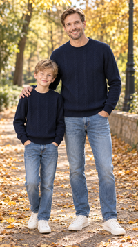 Dad and son in matching navy cable-knit crewneck sweaters.
