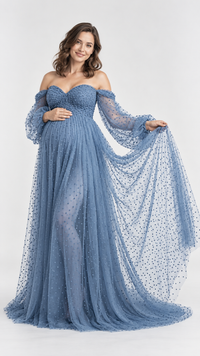 Pregnant woman in a dusty blue dotted tulle off-shoulder maternity gown in a photo studio