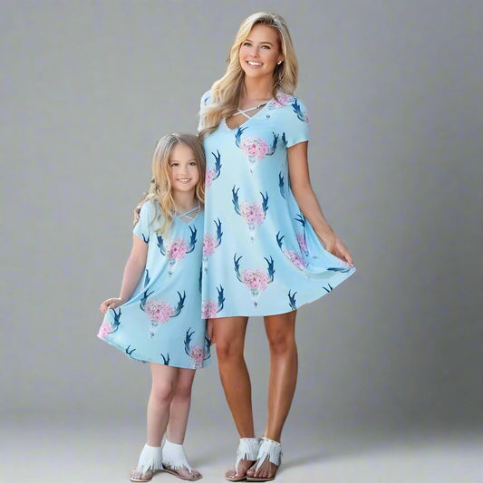 Mother and daughter wearing matching blue antler print dresses, styled for summer