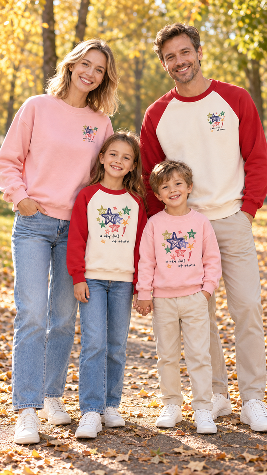 Family in matching pink sweatshirts with a colorful cluster of hand-drawn stars on the chest.