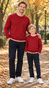 Dad and son in matching red crewneck knit sweaters with cream striped cuffs and hem.