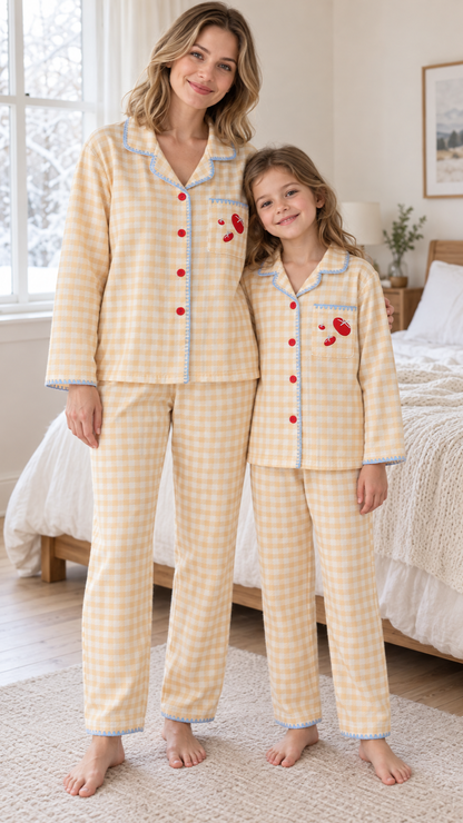 Mom and daughter in matching butter-yellow gingham button-up velvet pajamas with blue piping and a tomato pocket.