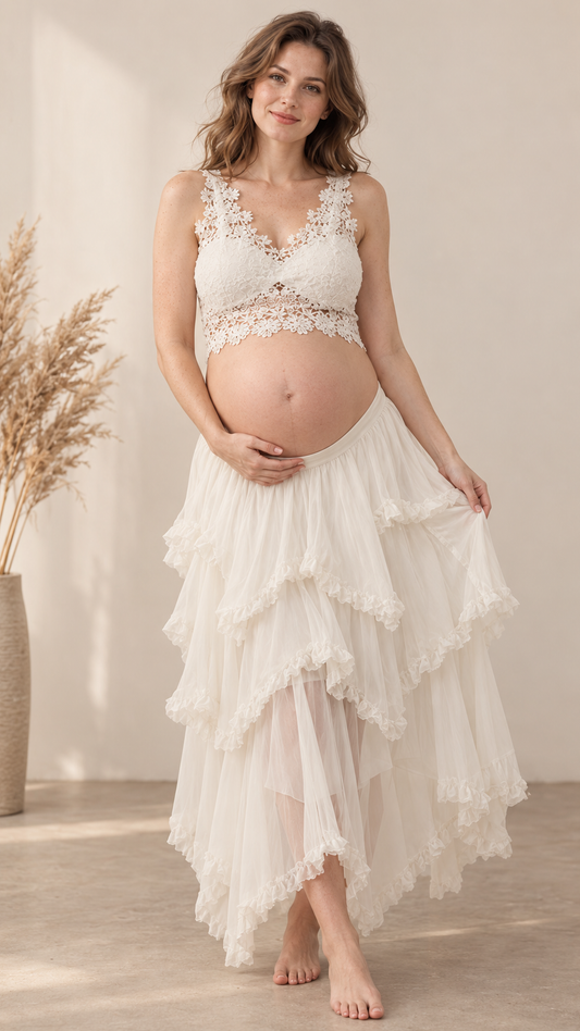 Pregnant woman in an ivory floral lace crop top and tiered ruffle skirt in a warm studio