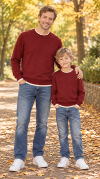 Dad and son in matching burgundy crewneck knit sweaters with cream trim.