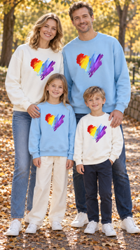 Family in matching white crewneck sweatshirts with a big rainbow scribble heart on the chest.
