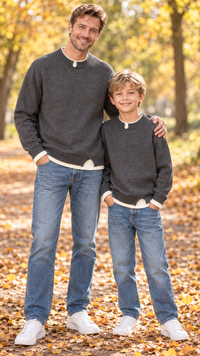 Dad and son in matching charcoal crewneck knit sweaters with cream layered hems.