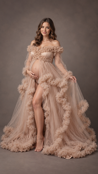 Pregnant woman in a nude blush ruffled tulle off-shoulder maternity gown in a photo studio