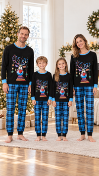 Family in matching black Christmas pajama tops with an ornament reindeer and sky-blue trim, worn with blue and black plaid pants.