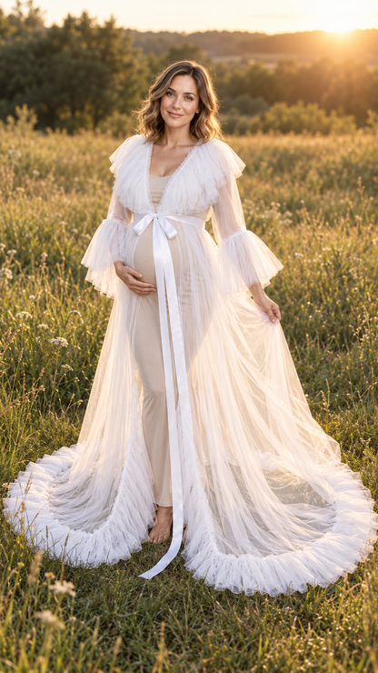 Maternity photoshoot outdoors at golden hour in a white sheer tulle gown with a long train