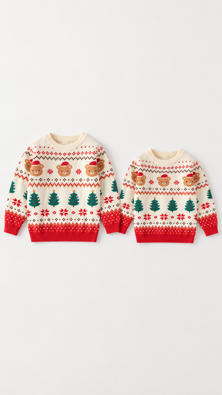 Two cream Fair Isle kids' Christmas sweaters with teddy bears, Christmas trees and red ribbed hems, laid flat.