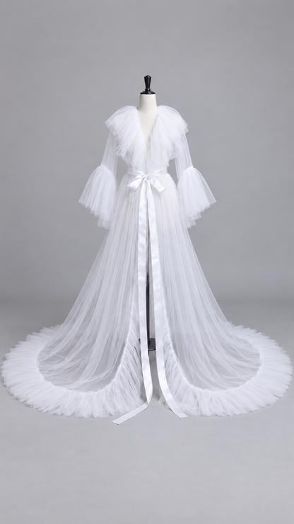 White sheer tulle maternity gown with a ruffled V collar and satin sash on a dress form