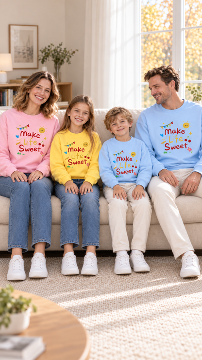 Family relaxing together at home in matching Make Life Sweet sweatshirts.
