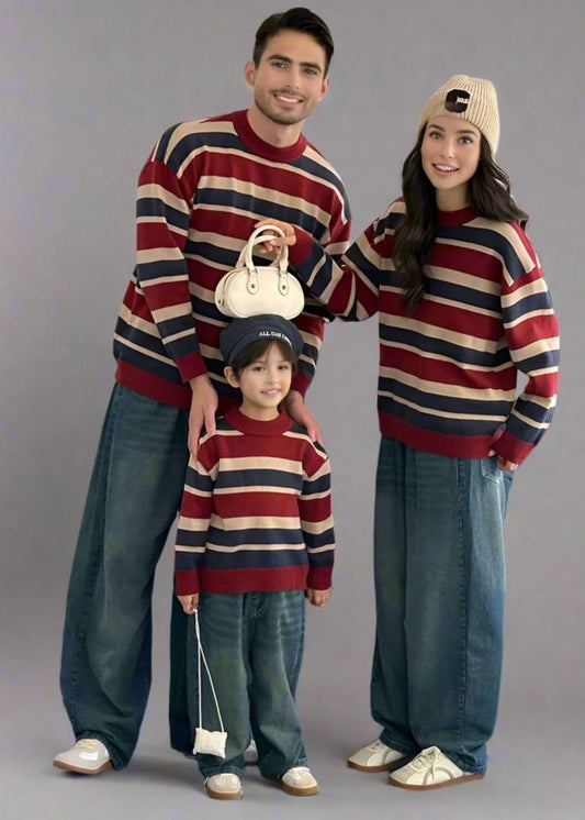 Family wearing matching red, blue, and beige striped sweaters with casual denim, perfect for a cozy coordinated look