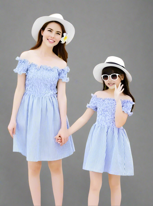 Mother and daughter in matching blue striped dresses and white hats, holding hand
